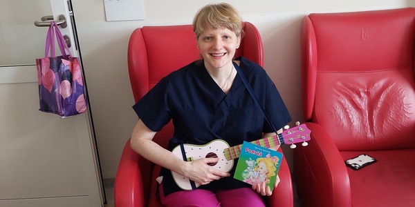 Nauczyciela gra na ukulele w trakcie czytania książki pt. Podróż