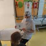 Nauczyciel w przebraniu za Panią Zimę pokazuje dziecku książkę o zimie