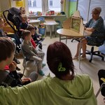 dzieci i rodzice oglądają przedstawienie nauczycielka przy stole pokazuje teatr kamishibai