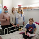 Wolontariuszki z panią z przedszkola przy łóżku dziecka