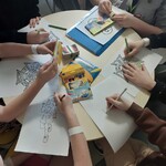 wychowankowie kolorują kredkami przy stole