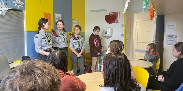 trzy harcerki stoją naprzeciwko pacjentów w szpitalnej świetlicy i opowiadają o harcerstwie