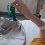 Dziecko trzyma zielonego włóczkowego robaczka  - pożeracza smutków