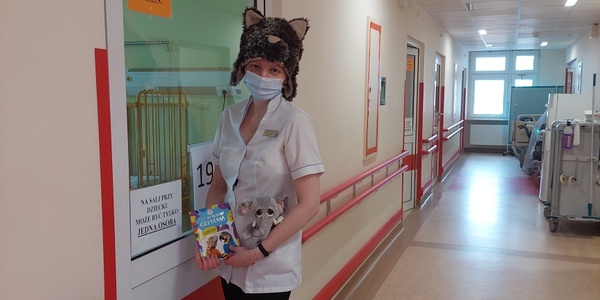 Nauczyciel w czapce Jaguara trzyma pluszowego słonika i książkę o zwierzętach egzotycznych