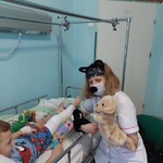 Nauczyciel w opasce z uszkami zabawia dziecko pacynką kotka i pieska