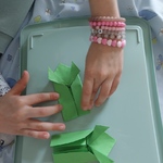 Dziecko wykonuje żabkę z papieru składając ją w technice origami