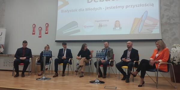 uczestnicy konferencji siedzą w półokręgu podczas debaty