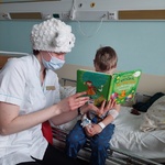 Nauczyciel w czapce baranka czyta dziecku książkę - O wiośnie, kurczętach i wielkanocnych świętach