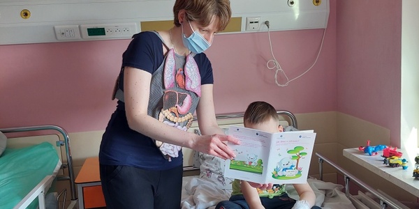 Nauczyciel ubrany w kamizelkę edukacyjną - Ciało człowieka, czyta dziecku - Jak dbać o zdrowie