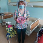 Nauczyciel w przebraniu w pluszowych uszkach i nosku zajączka trzyma koszyczek z jajeczkami wypełnionych zagadkami
