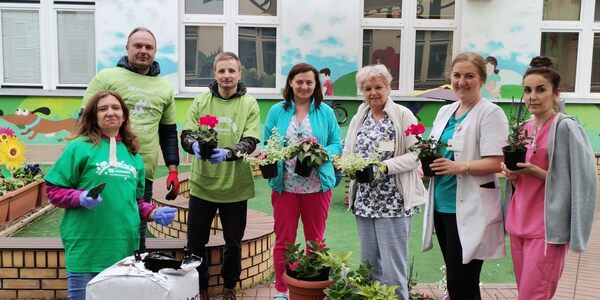 wolontariusze pielęgniarki, oddziałowa kliniki rehabilitacji i nauczycielka szkoły trzymają kwiaty w rękach
