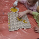 dzieci przygotowują plaster miodu malując wytłaczankę do jajek na żółto