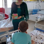 Nauczycielka w żabim przebraniu prezentuje dziecku książkę o jeziorze i jego mieszkańcach