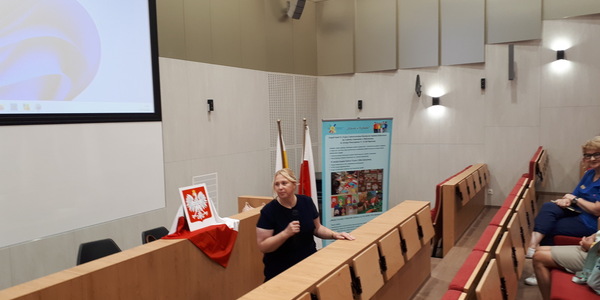 Aula, dyrektor szkoły z mikrofonem stoi przez widownią