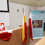 w stojaku flaga polski i flaga z barwami miasta Białystok z tyłu baner z reklamą szkoły obok flag godło Polski