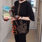 Nauczycielka trzyma książkę w przebraniu za stwora Gruffalo - w czapce przedstawiającej jego głowę i w nakładanych łapkach, z pluszakiem Gruffalo i myszką