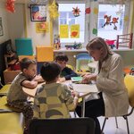 Nauczycielka i trzech chłopców siedzą przy stoliku w świetlicy i rozmawiają na temat wiersza.