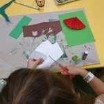 Dziewczynka siedzi przy stoliku i wycina nożyczkami z papieru.