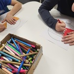 pacjenci rysują kredkami bombki obok leży pudełko z kredkami