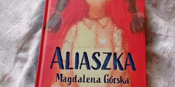 na białym materiale leży książka pt. Aliaszka Magdaleny Górskiej